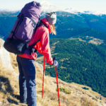 female hiker using trekking poles walking down a steep slope