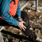 Hiker sitting down resting holding his painful knee
